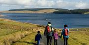 Teulu yn cerdded i gyfeiriad Llyn Brenig