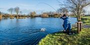 Man casting a fishing rod into trout lake