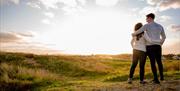 Couple watching the sunrise on the Kinmel Dunes