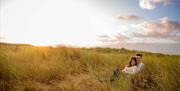 Couple sitting in Kinmel Dunes with sunrise overhead