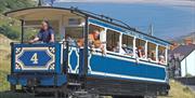 Tram Llandudno yn dringo i fyny Y Gogarth gyda Bae Llandudno yn y cefndir