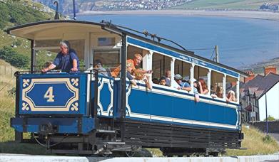 Tram Llandudno yn dringo i fyny Y Gogarth gyda Bae Llandudno yn y cefndir