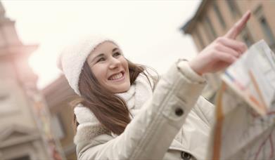 Person pointing forward in a white jacket and hat
