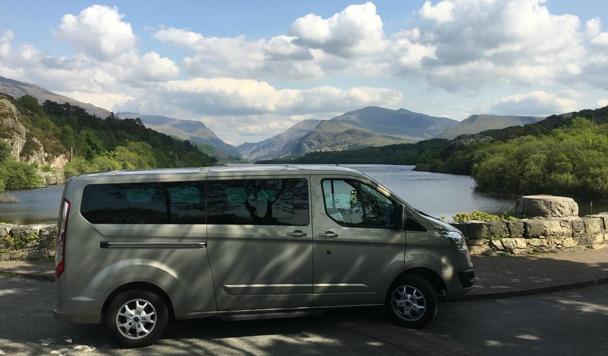 mini tour bus parked next to lake with views of the Snowdonia Range