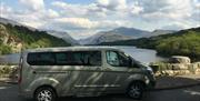 mini tour bus parked next to lake with views of the Snowdonia Range