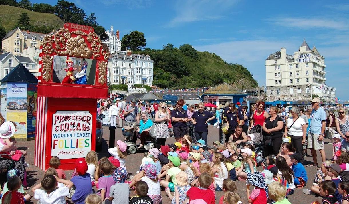 Children and families watching the Punch and Judy show in Llandudno.