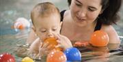 Mother and child playing with balls in swimming pool