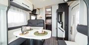 Image of black and white dinning area inside the motorhome with dining crockery on display.