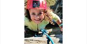 Smiling young girl with red helmet in climbing gear