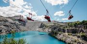 Four riders on Velocity zip wire over Penrhyn Quarry lake