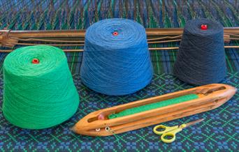 Image of green, blue and grey wool next to tools.