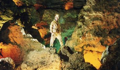 Man standing in a cave with a helmet and light