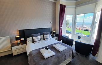 Double room with bay windows and seating area with views onto the sea front in Llandudno