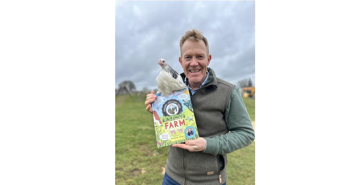 Adam Henson holding his book and a chicken