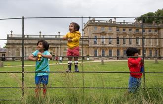 Children playing on a fence by a large house