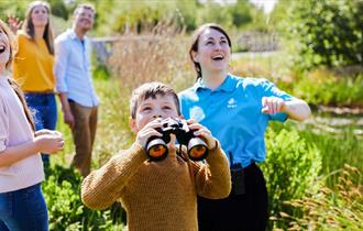 Family out in nature, a child is holding binoculars and looking up