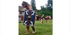 Woman dressed as a gladiator and carrying a large blue shield at the Gladiator Weekend at Chedworth Roman Villa