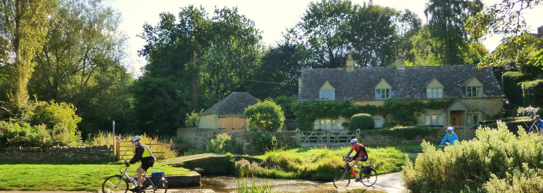 Group cycling through a picturesque Cotswold village with Bainton Bikes