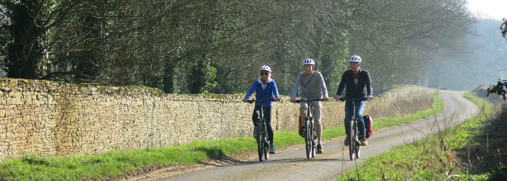 Group cycling along a misty lane on electric bikes hired from Cotswold Ebikes