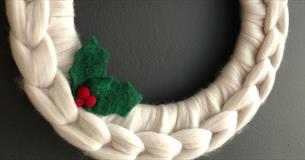 Chunky knitted white festive wreath with one piece of green holly and berries