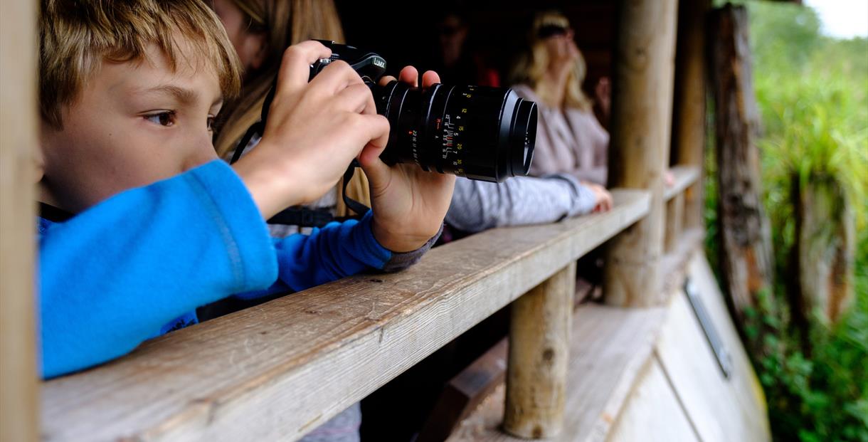 Child with camera in bird hide