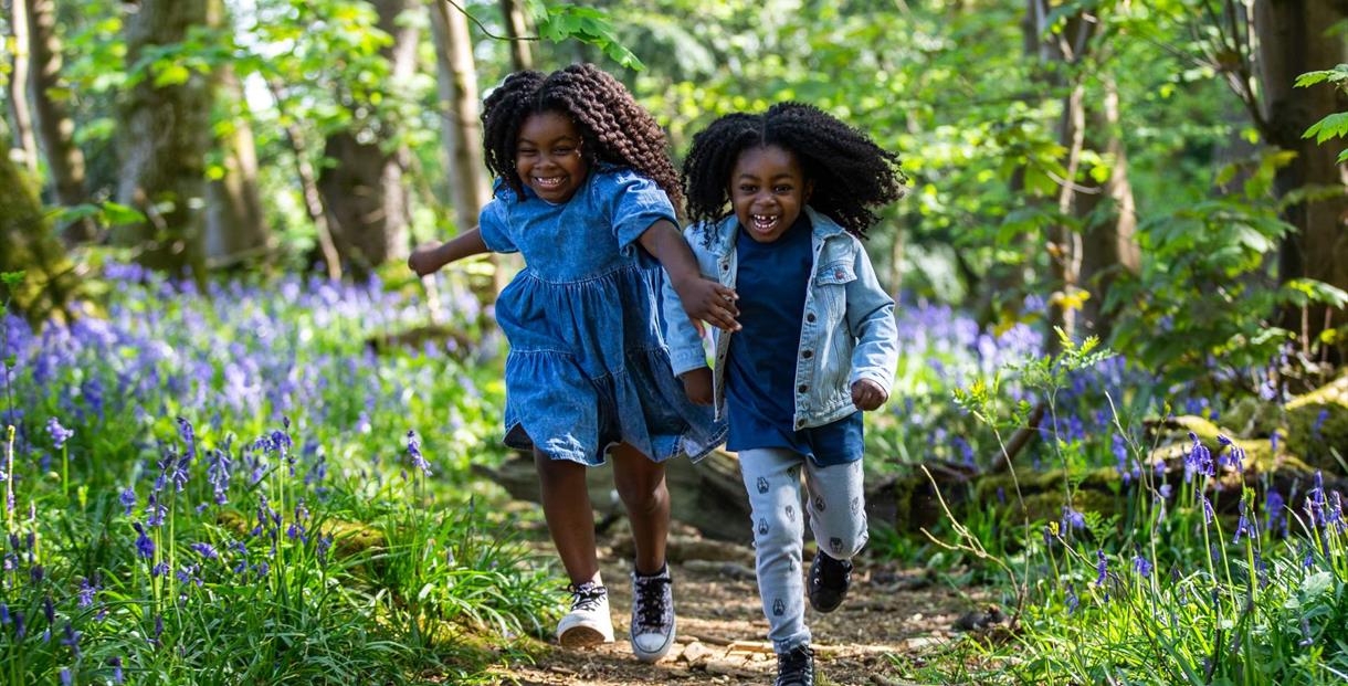 two girls running through spring woodland