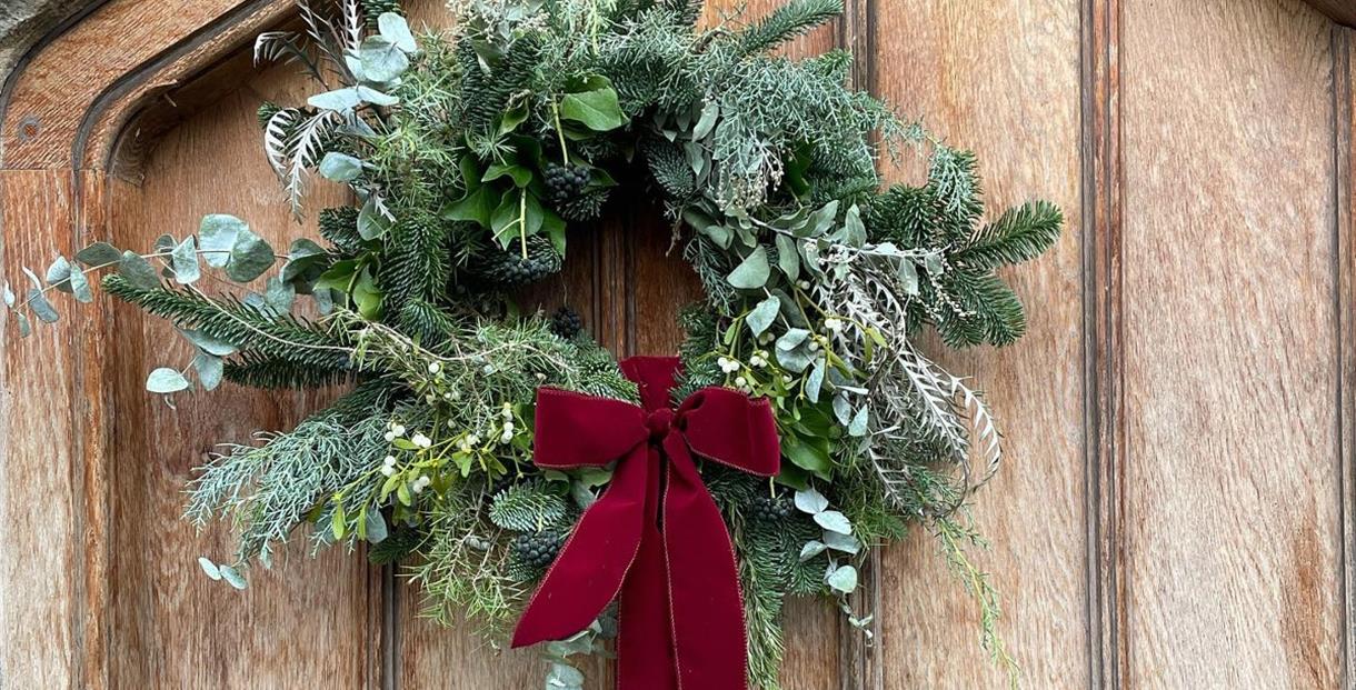 A wreath of foliage and ribbon hanging on a door
