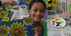 A child holding up a piece of artwork