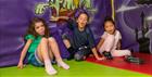 Three children sat down in the soft play area