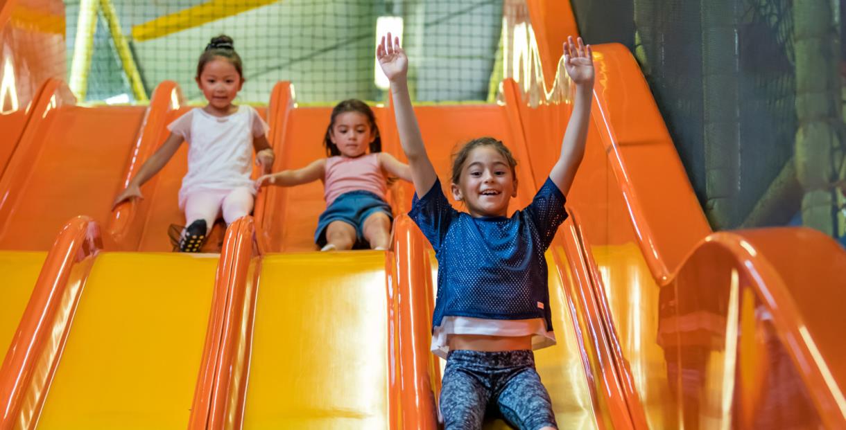Three children sliding down the slide