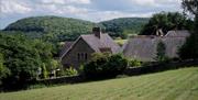 landscape photo of the house with filed in forefront and rolling hills in the background