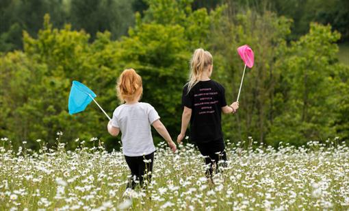 Two children searching for insects in a field
