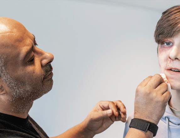 Christian Kotey  painting a teens face