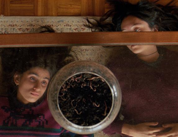 two young girls looking upwards through a glass coffee table