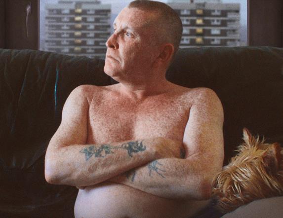 Man with tattoos looking out the window