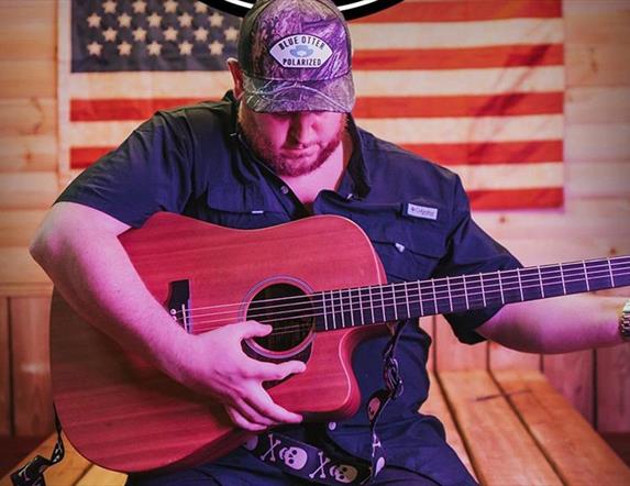 Man strumming guitar in front of American flag