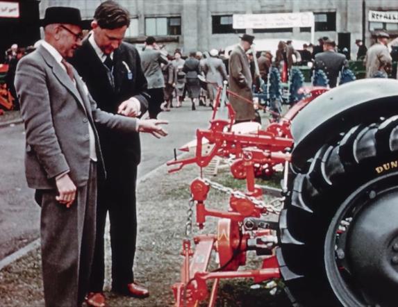 Two judges inspect farm equipment at a fair.