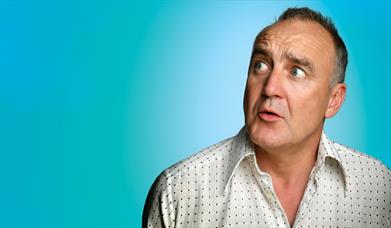 Jimeoin looking to his left side, confused, against a  bold, light blue background.