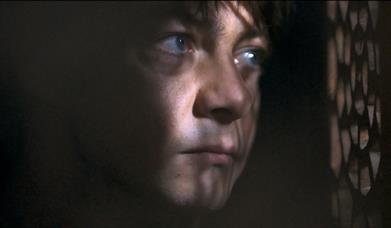 man suspiciously looking through curtains