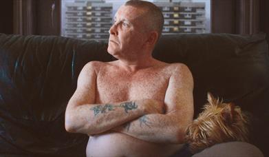 Man with tattoos looking out the window