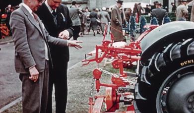 Two judges inspect farm equipment at a fair.