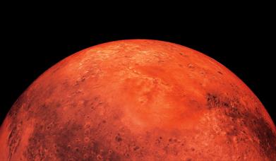The planet Mars as seen from space, a red sphere surrounded by black.