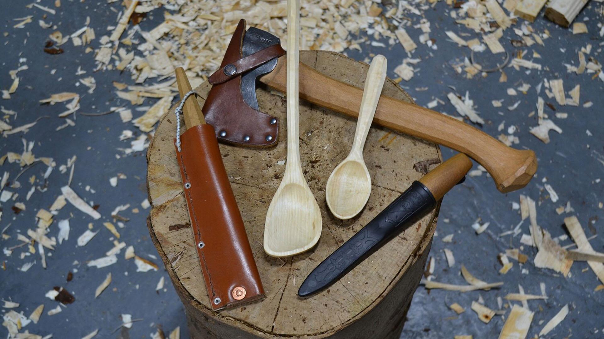 A photograph of wood-whittling tools and a carved spatula and spoon.