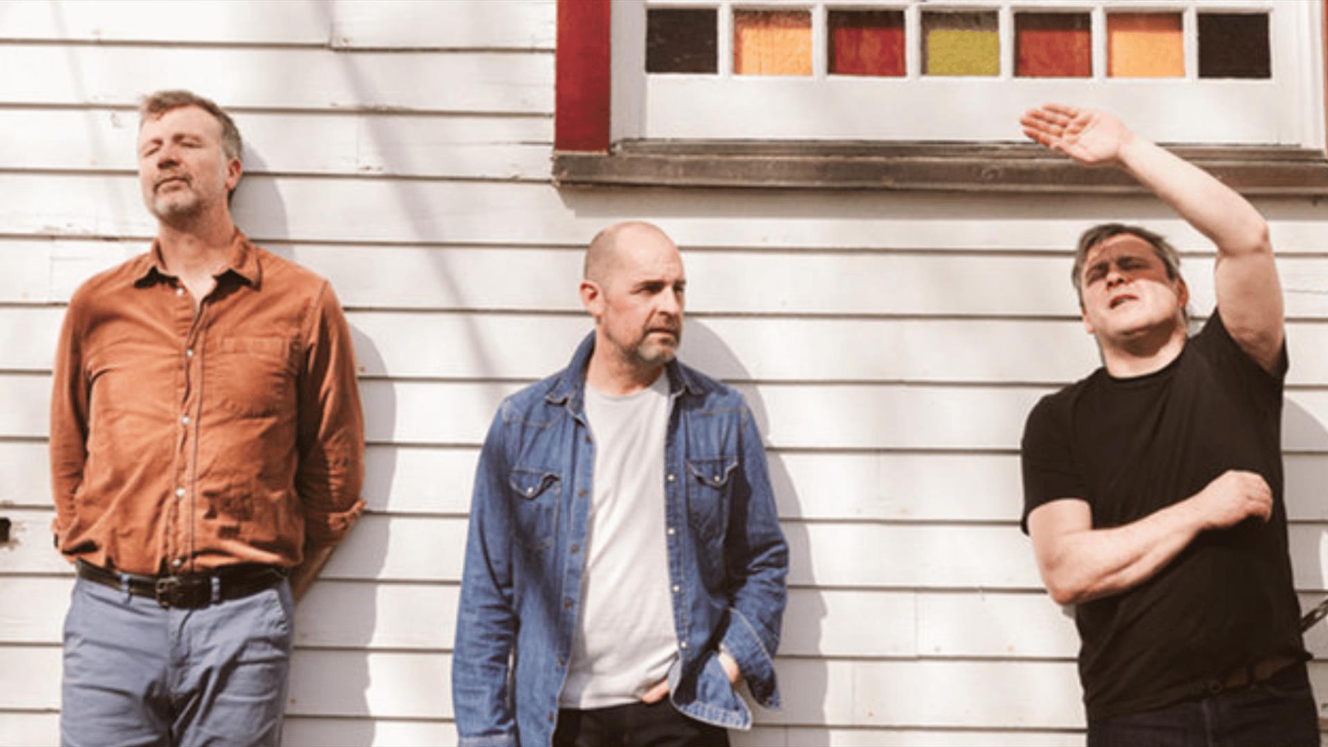 Members of Bell X1 posing for a photo in front of  a white  house.