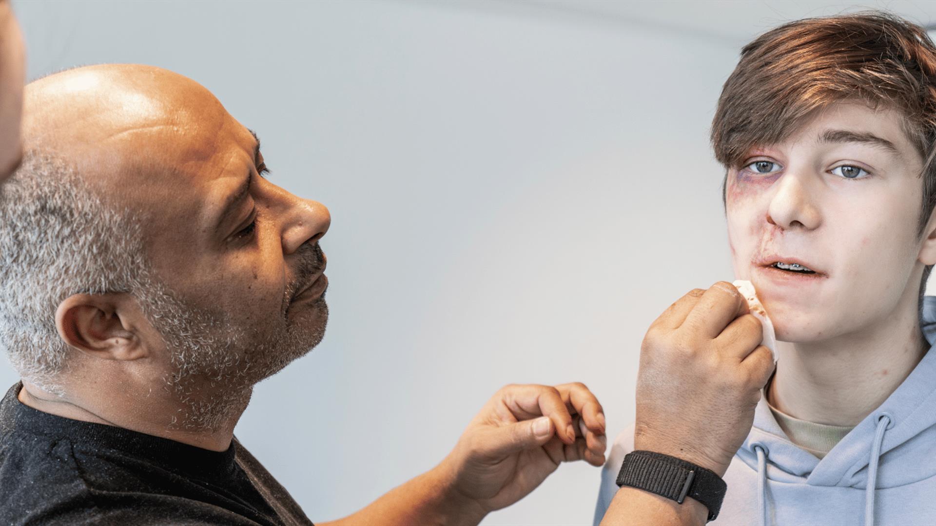 Christian Kotey  painting a teens face