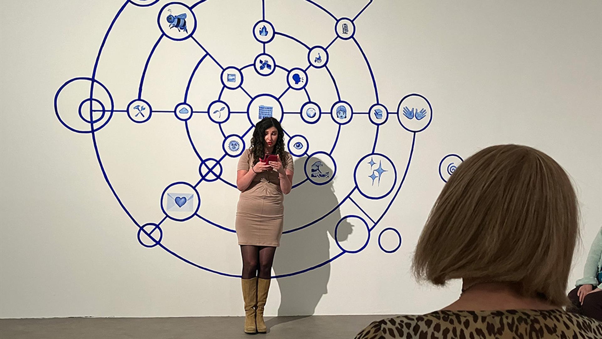 Woman stands in front of an audience reading