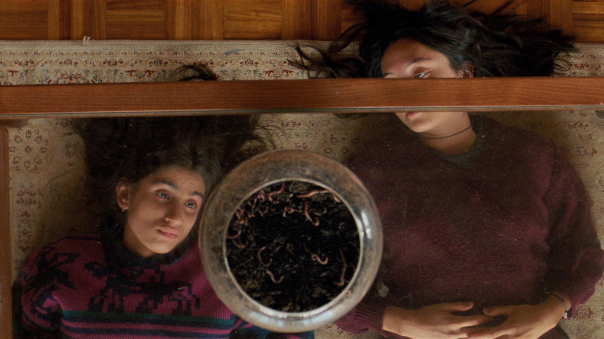 two young girls looking upwards through a glass coffee table