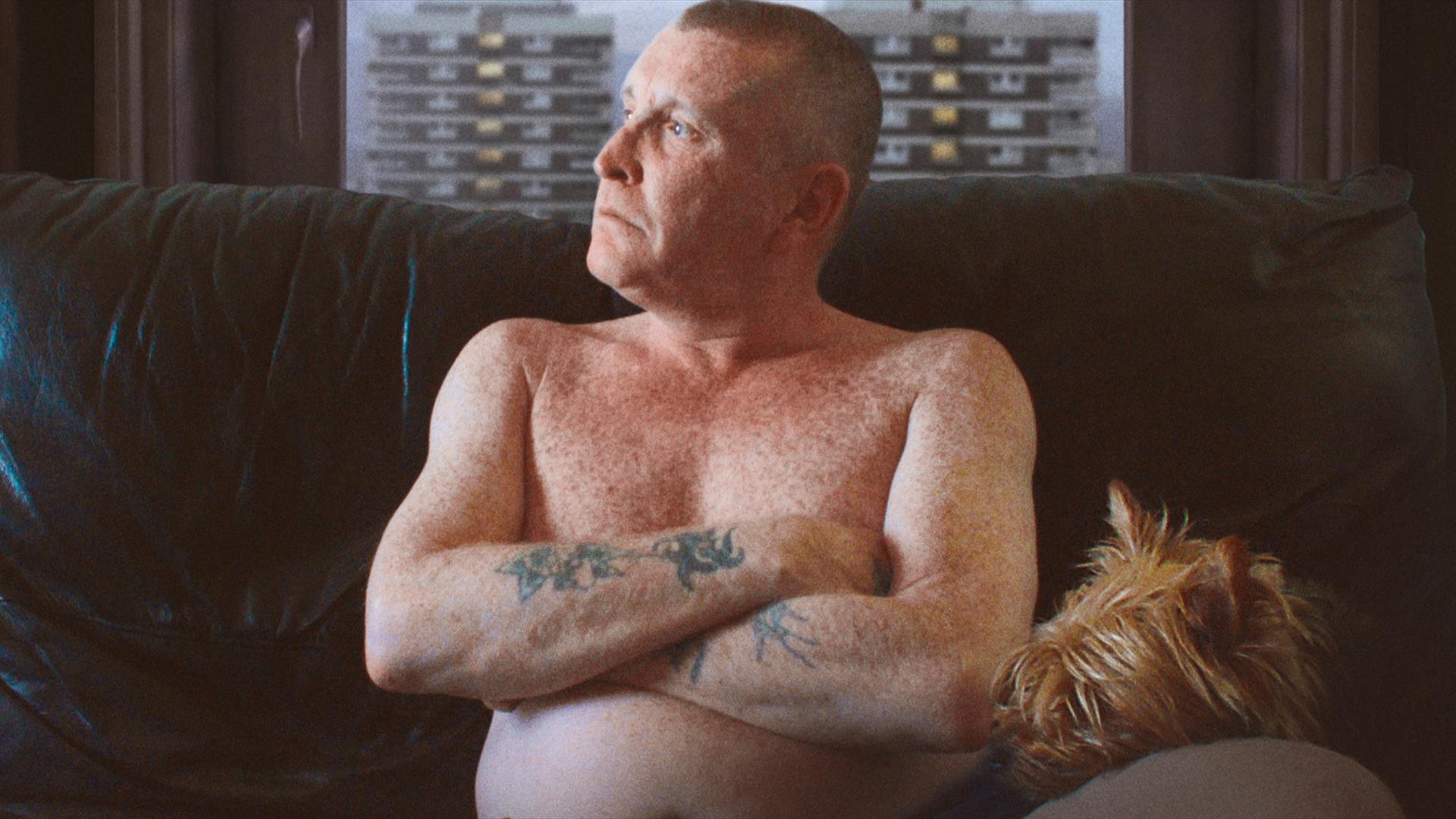 Man with tattoos looking out the window
