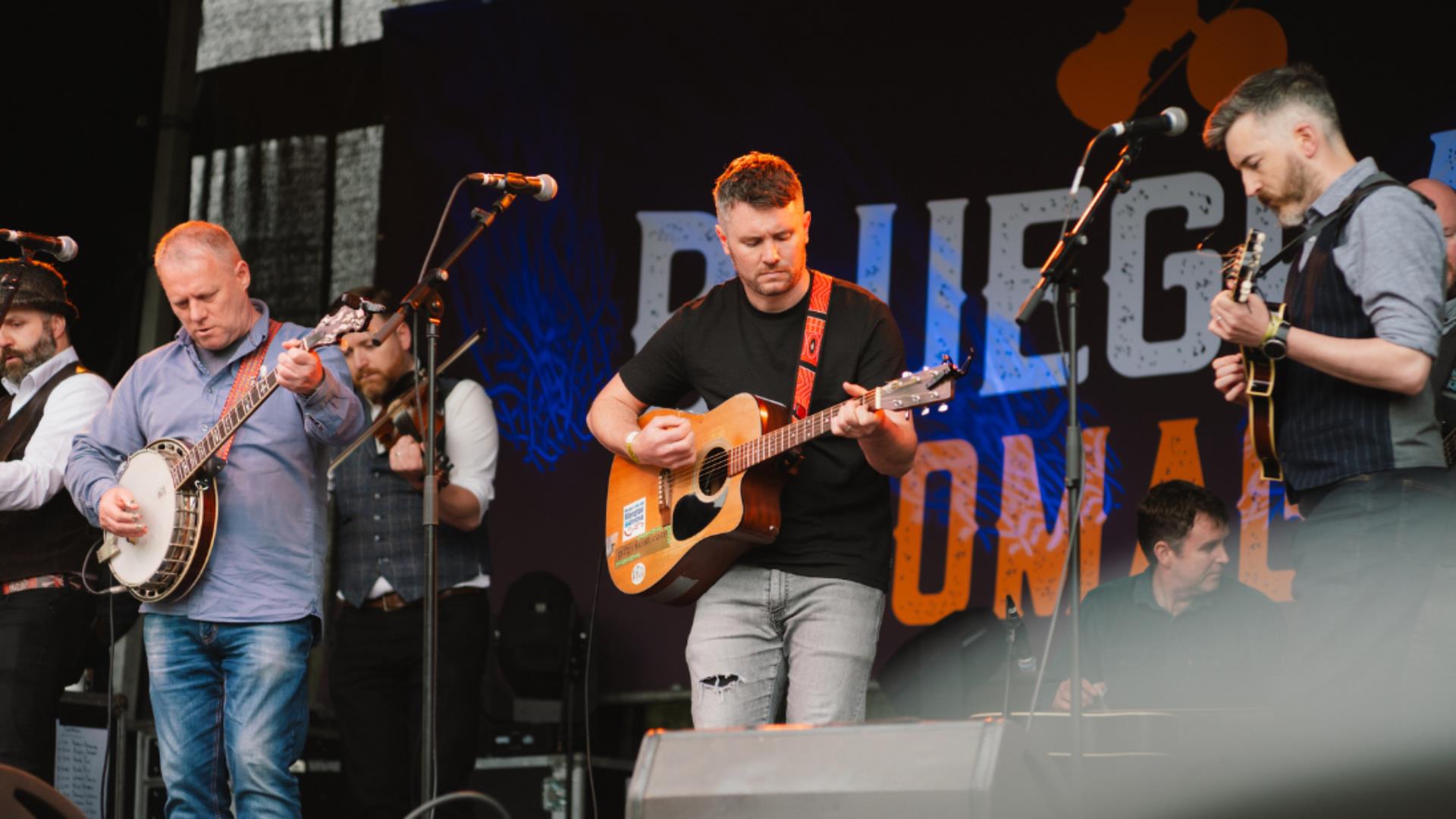 A man in a black tshirt playing guitar on stage, the band Pilgrim Street