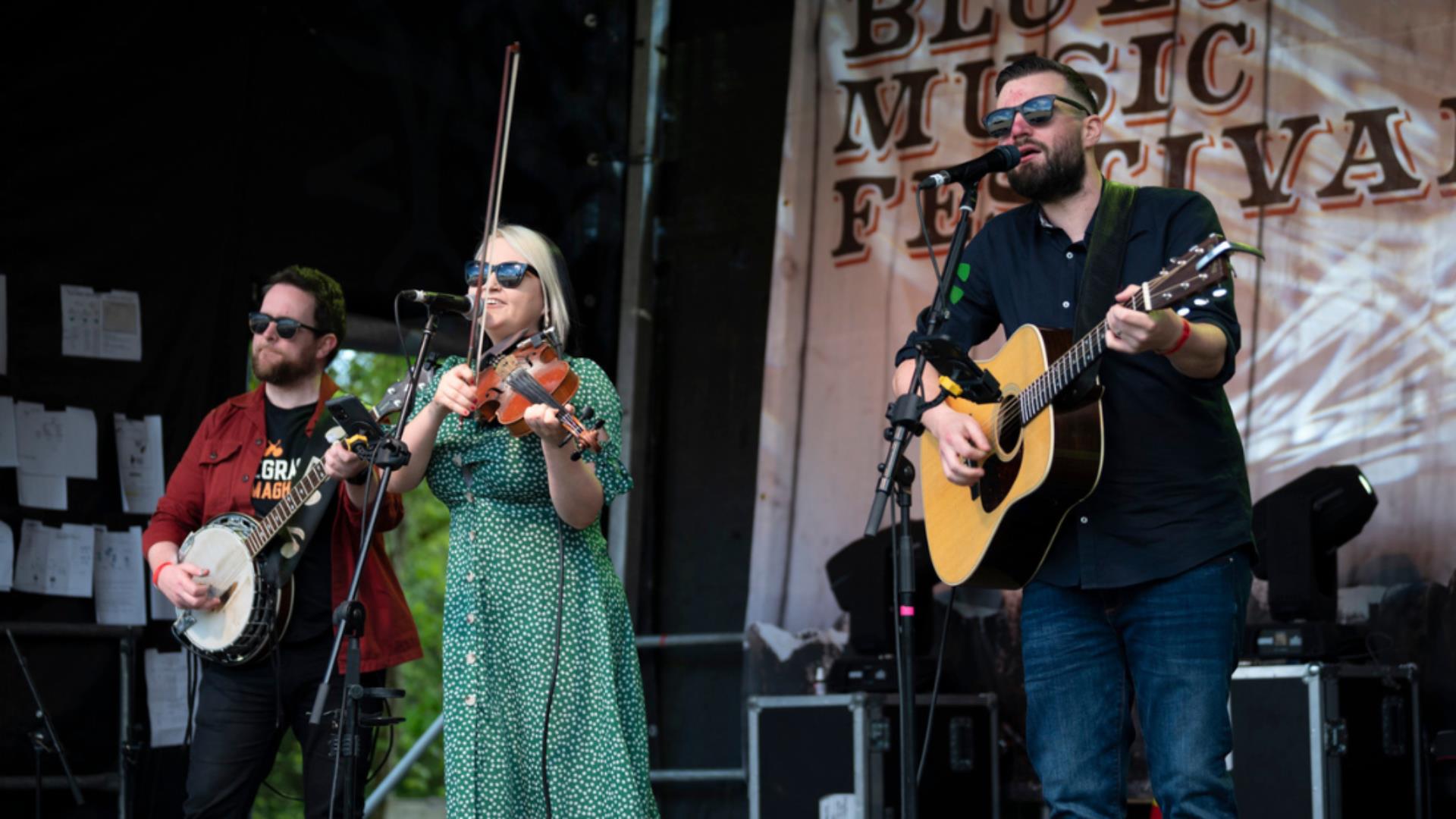 Men and woman in a band playing music on a stage.